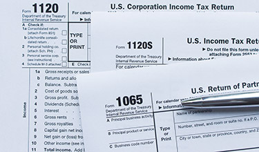 Photo of a silver pen on top of a stack of US Corporate Income Tax Return forms
